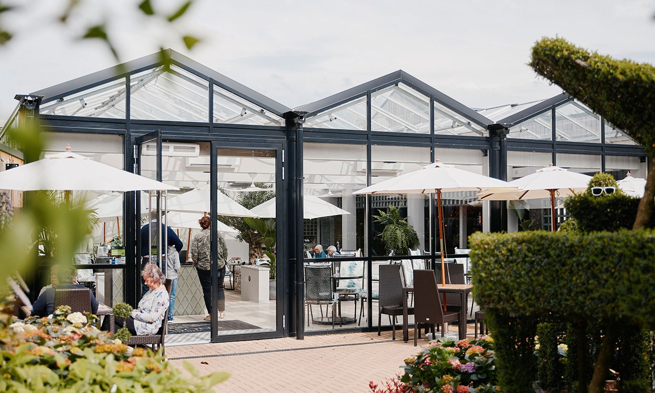 The Glasshouse Restaurant at Lavershot Barns, Windlesham — the glasshouse pavilion and terrace with guests and parasols outside
